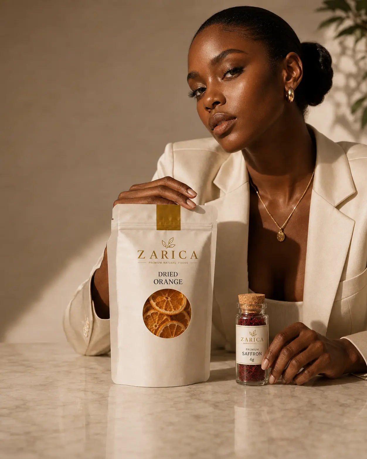 Model in an ivory suit presenting a ZARICA dried orange pouch beside a saffron vial